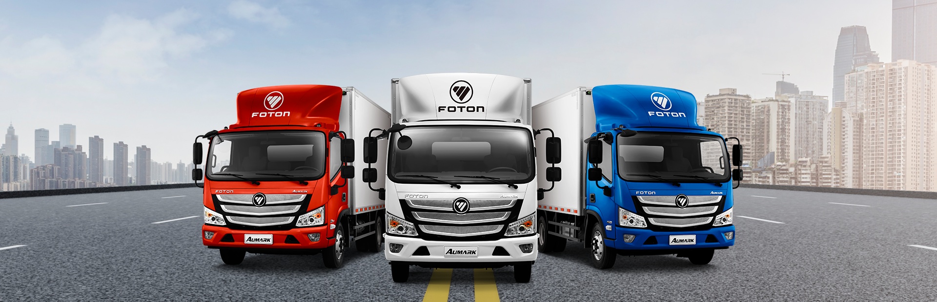 Banner com 3 caminhões da marca FOTON, um vermelho, um branco e um azul, da esquerda para a direita respectivamente.